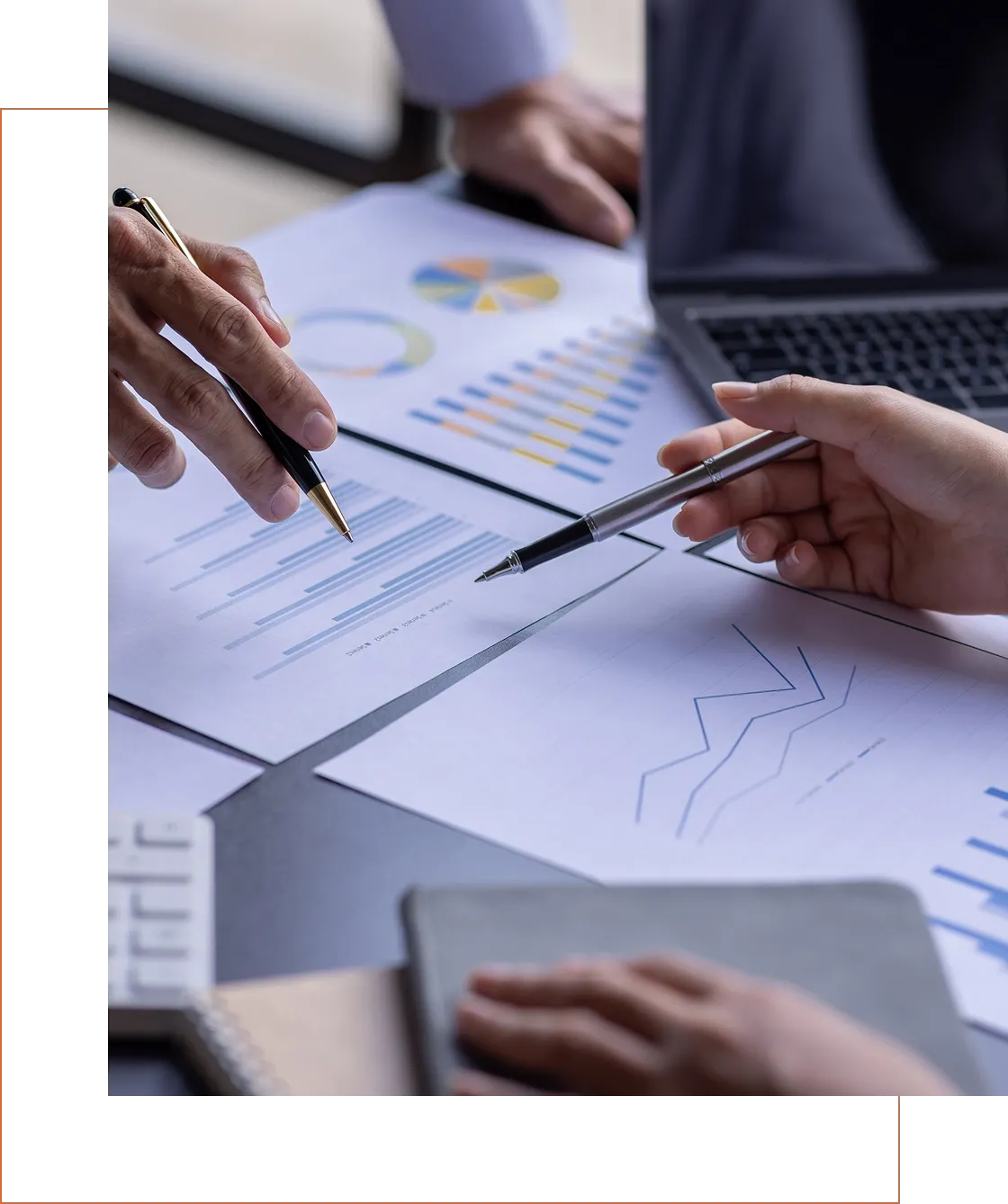 Hands discussing charts and graphs on a table